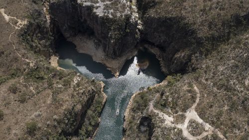 Туристическая лодка плывет по долине озера Фурнаш, недалеко от города Капитолий, Бразилия.  Огромный кусок камня отломился от стены каньона и упал на баржи.