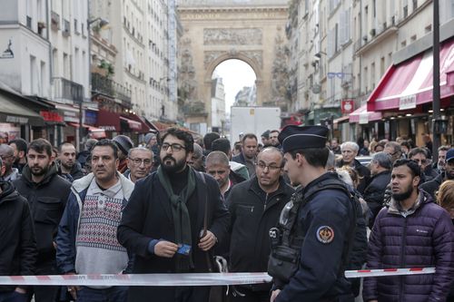 Bystanders gather behind the crime scene tape where a shooting took place in Paris, Friday, Dec. 23, 2022 