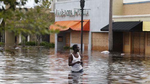 John Duke wades through a flooded street to try to salvage his flooded car in Jacksonville. (Associated Press)