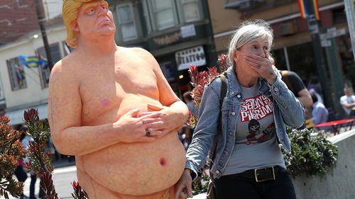 A woman stands beside a statue of a naked Republican presidential candidate Donald Trump, in New York's Union Square. The statue was removed by New York City Department of Parks &amp; Recreation employees. (AAP)