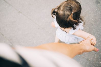 Young mum walking with toddler daughter.