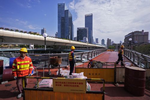 Workers refurbish an overhead pedestrian bridge in Shanghai on Oct. 9, 2024 