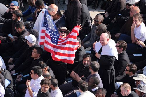 A man waves a US flag prior to the inaugural Mass of Pope Leo XIV.