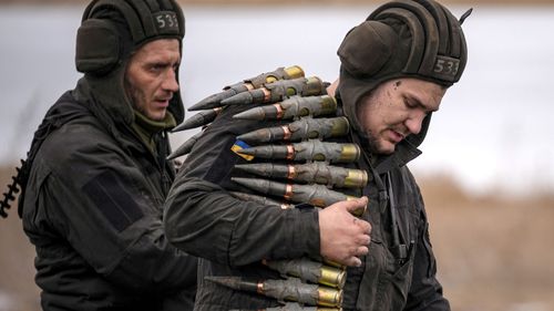 A Ukrainian serviceman carries large calibre ammunitions to be loaded on to armoured vehicles set to fight Russian invading forces.