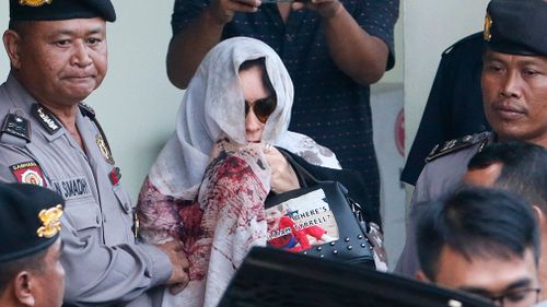 Australian Schapelle Corby is escorted by Bali Police at the parole office in Denpasar, Bali, Indonesia. (AAP)