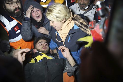 Rescuers and mother surround Adnan Mohammet Korkut after he was rescued in Gaziantep, southern Turkey, early Friday, Feb. 10, 2023.