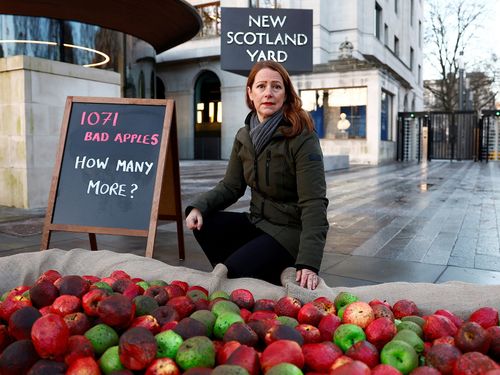 PDG de Refuge, Ruth Davison pose avec des pommes pourries en plastique lors d'une manifestation devant New Scotland Yard à Londres.