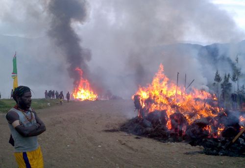 A West Papuan man looks on at a burning house during election violence in 2011.