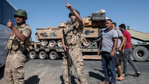 Turkish soldiers secure the area as Turkish military vehicles carry tanks to the Syrian border in Akcakale, Turkey.