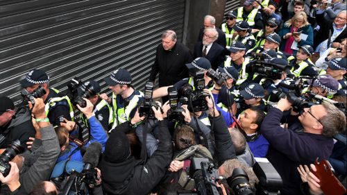 Circled by police, Cardinal Pell walked with his head down towards his lawyers office.