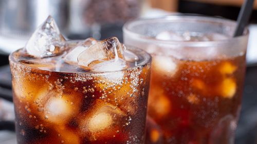 cola with crushed ice in glass and there is water droplets around. cool black fresh drink.