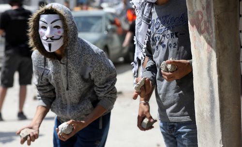 A Palestine rioter wearing an Anonymous mask and bearing rocks risks his life. Picture: EPA 