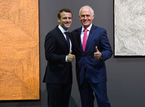 The pair guive cameras the thumbs up in front of paintings by Australian artist George Tjungurrayi. (AAP)