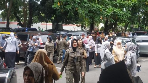 People wait outside after they evacuate a government building following an earthquake, in Makassar, South Sulawesi, Indonesia. 