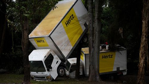Hertz hire vans are tossed into a creek and up a tree as floodwaters recede in Lismore. (AAP)