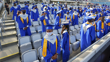 Graduates of the Frank H. Peterson Academies of Technology stand as classmates file in to their socially distanced seats at the start of Friday morning&#x27;s graduation ceremony in TIAA Bank Field. 