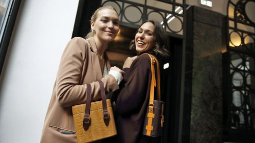 Model Arizona Muse, left, is flanked by designer and Officina del Poggio owner Allison Hoeltzel Savini as they present a creation of the Officina del Poggio women's Fall-Winter 2019-2020 collection, in Milan, Italy (Photo: Feb 2019)