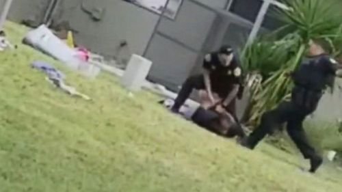 In the video, taken by a Miami resident on Thursday morning, the suspect holds his hands behind his back as he lies face-down on the grass. (ABC News US)