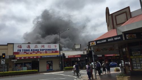 The fire has spread to the shared roof space of three other businesses. (9NEWS)