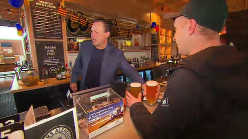 Crows legend Tony Modra pours beers for fans. 