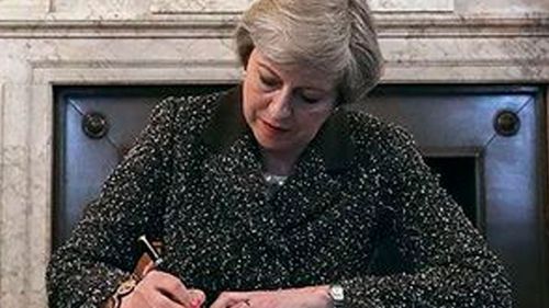 UK Prime Minister Theresa May formally signs a letter handed to EU Council President Donald Tusk in Brussels. (AFP)