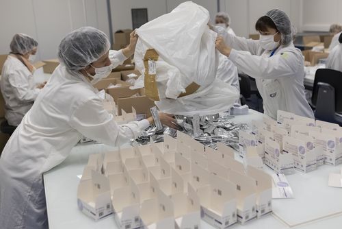 Employee work on an assembly line at NG Biotech, a start-up that makes an array of medical tests, including kits for use at home and by medical professionals to detect COVID-19 infections, in Guipry, western France, Friday, Jan. 7, 2022.