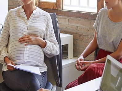 Pregnant woman sitting with colleagues at work