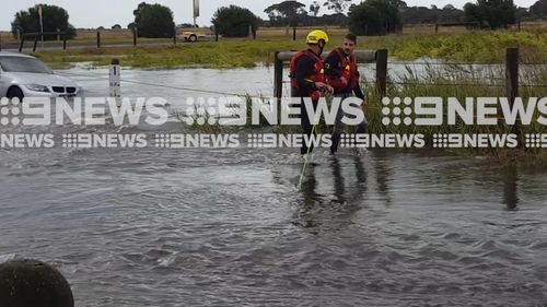 The driver walking away from his car with a rescuer. (9NEWS)
