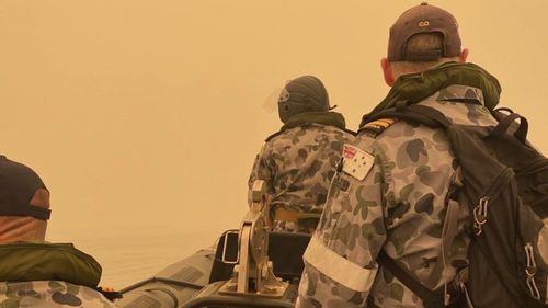 In this photo provided by the Australian Defence Force a tender from HMAS Choules motors through smoke haze off the coast of Mallacoota, Australia, Thursday, Jan. 2, 2020. (ADF via AP)