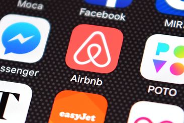 The Airbnb app logo is displayed on an iPhone 