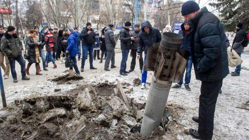 People look at a missile embedded in the street after a shelling. (Getty)