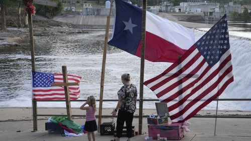 Nancy Epperson, right, and Brooklyn Pucek, 6, visit a memorial for flood victims along the Guadalupe River on Thursday, July 10, 2025, in Kerrville, Texas. (AP Photo/Gerald Herbert)