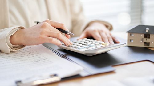 Woman budgeting with calculator and bills