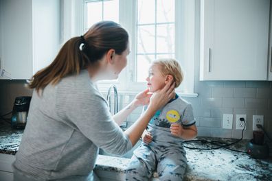 Children, Kitchen, Breakfast - Mother checking son's ear in the kitchen