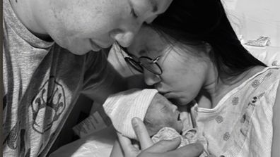 Black and white picture of mother and father holding baby.