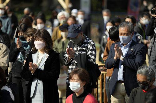 Visitors pray for a minute of silence for the victims of the March 11, 2011 earthquake and tsunami during a special memorial event Friday, March 11, 2022, in Tokyo, Japan 