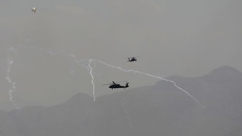 Anti-missile decoy flares are deployed as US Black Hawk military helicopters and a dirigible balloon fly over the city of Kabul.