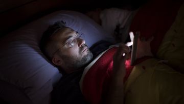 Man on phone in bed at night