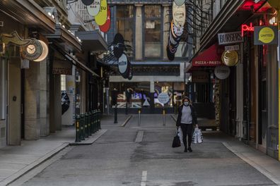 A lone shopper is seen carrying shopping bags as she walks down the usually busy Degraves Street laneway fame for its cafes and coffee as lockdown of Melbourne forces people to stay at home if not working due to the continuing spread of COVID-19. (Asanka Brendon Ratnayake)