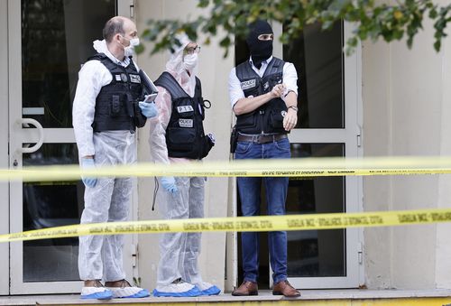 French investigating officers stand in front of the Gambetta high school in Arras, northeastern France, after a man armed with a knife killed a teacher and wounded another teacher and a security guard, an attack being investigated as potential terrorism, Friday Oct. 13, 2023.