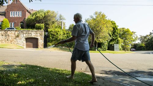 A man waters his garden with a hose in Sydney's Vaucluse. 