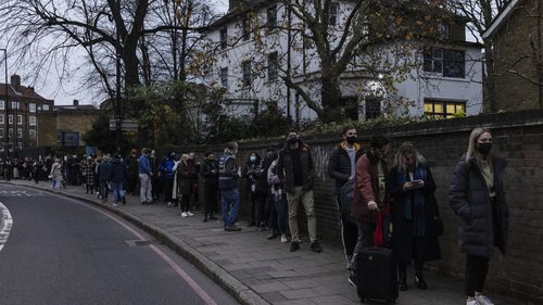 People queue up to receive their booster shots, which Chief Medical Officer Prof Chris Witty said can help build immunity against Omicron. 