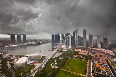 Thunderstorm with heavy dark clouds and rain over the skyline of Singapore. Falling rain and some grain are visible.