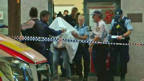 Police escort a person from the premises at Kogarah.