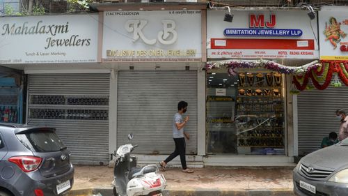 In this photo taken on July 31, 2020, pedestrians walk past closed gold jewelry stores in Mumbai.  Sales are down and artisans are staying home due to fear of the coronavirus.