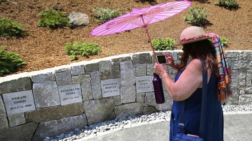 Karla Hailer, a fifth-grade teacher from Scituate, Mass., shoots a video where a memorial stands at the site in Salem, Mass., where five women were hanged as witches.