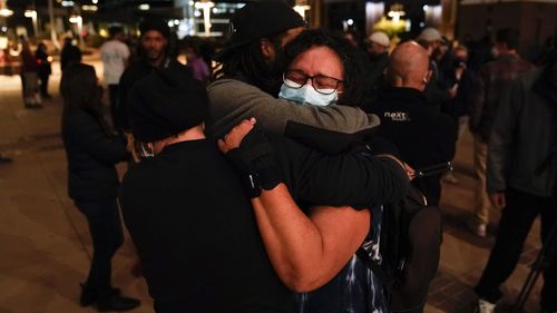 Three film industry workers comfort one another during the candlelight vigil. 