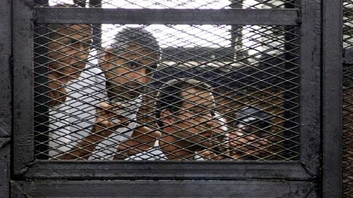 Australian correspondent Peter Greste, Canadian-Egyptian acting bureau chief of Al-Jazeera Mohamed Fahmy, and Egyptian producer Baher Mohammed, appear in a defendant's cage in a courtroom in Cairo, Egypt (AP Photo/Heba Elkholy, El Shorouk Newspaper, File).