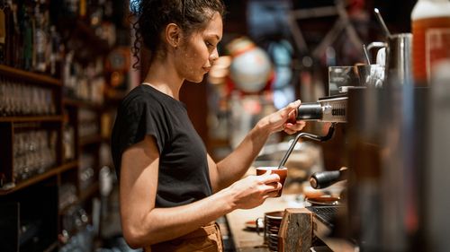 Informações aborígines na máquina Black Censilia Works Lorem Espresso, demonstrando os especialistas de habilidades de preparação de café no aquecimento do ambiente de estojo com uma configuração tradicional de bar.