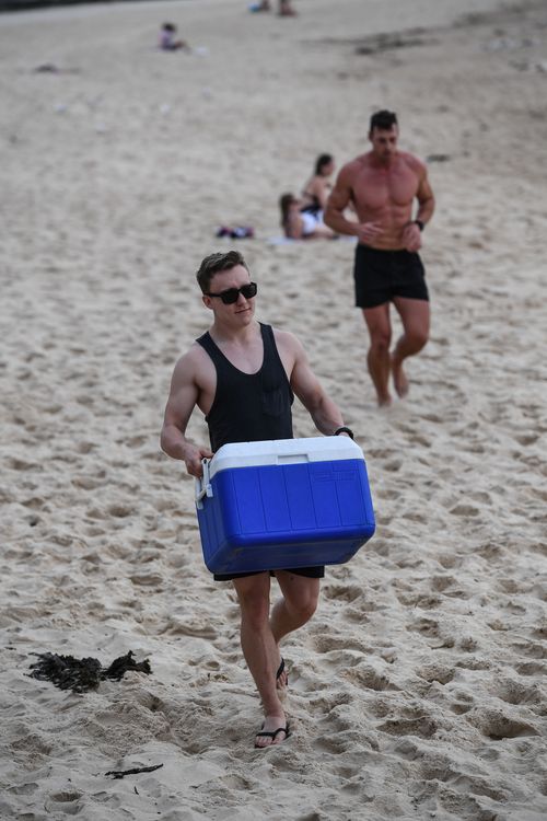 Beachgoers are seen during sunrise at Coogee beach in Sydney